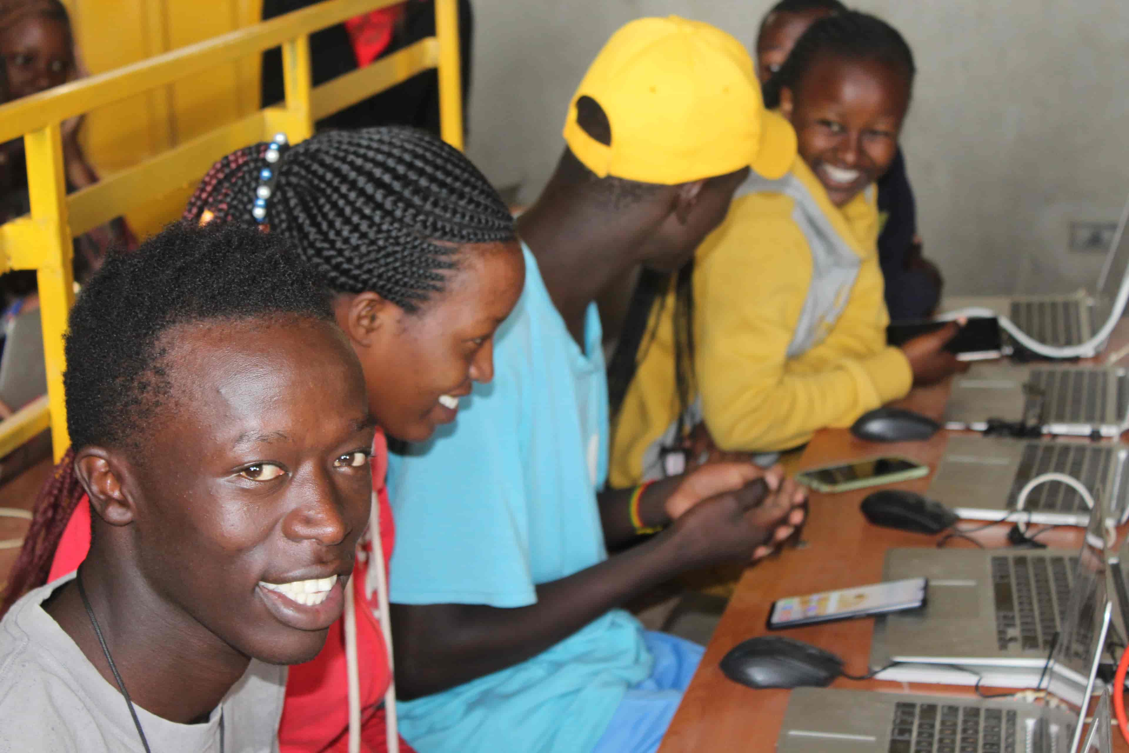 Kenya youth smiling with phones, laptops and mice